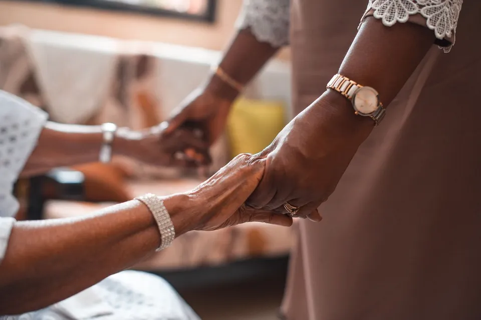 Two people holding hands in a gesture of care and support.